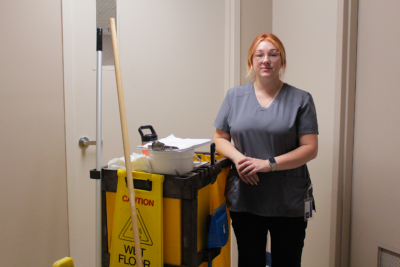 An Environmental Services worker standing by her cart.